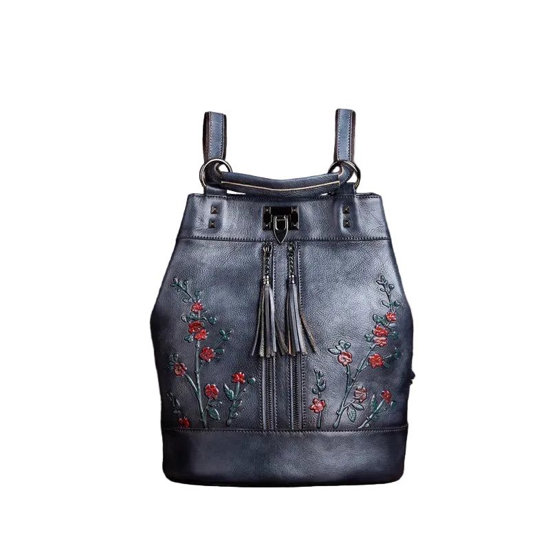 Blue leather handbag with floral embroidery on a brown textured background